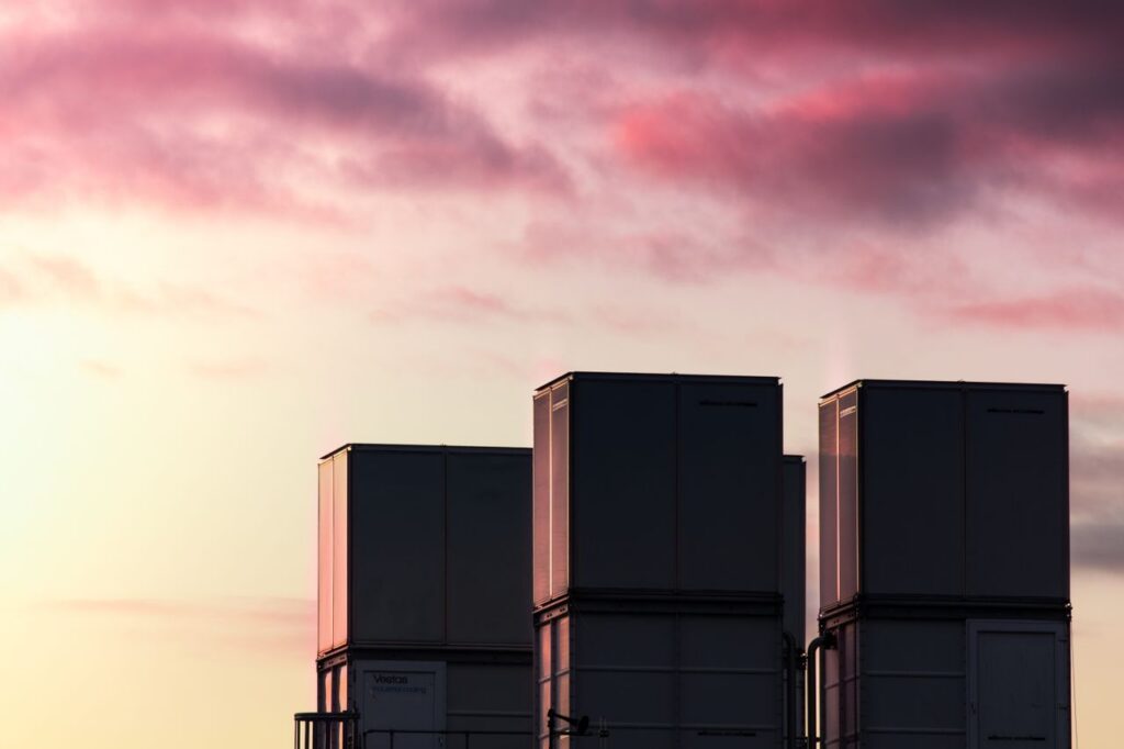 pexels photo 3535480 Silhouetted industrial containers against a vibrant sunset sky with pink clouds.